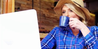 美女一边喝咖啡一边用笔记本电脑