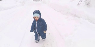 在冬季公园散步的小男孩。小朋友在雪地上踏出第一步。