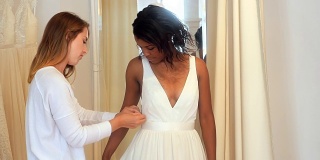 女人试穿婚纱与时装设计师的协助
