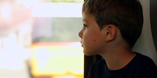 小男孩乘火车旅行。孩子望着火车窗外。孩子在火车窗外观察
