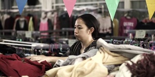 东南亚女孩寻找服装从大商店与吨和成堆的时尚配件