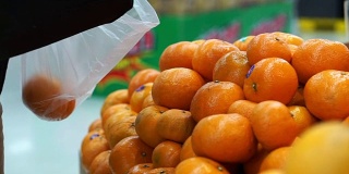 手摘橘子装袋。在消费品中过度使用塑料。世界污染问题