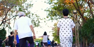 亚洲老年夫妇在公园里跳舞做有氧运动。一起欢笑，一起玩乐