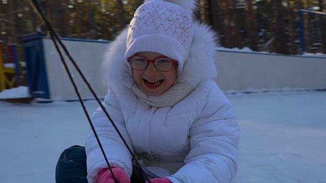 小女孩骑着雪橇。女孩很喜欢坐雪橇。女孩笑着和表情从快速滑雪橇。冬天孩子们的娱乐。