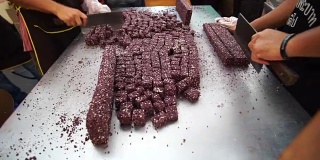 制作中国芝麻花生零食条。在金属桌上用刀切割