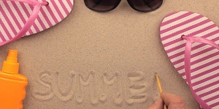夏天的题字手写在沙滩上，沙滩配件之间