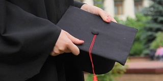 毕业日，女学生身着长袍，手拿带流苏的学位帽