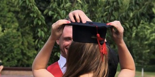 快乐的男学生拥抱姐姐，把他的毕业帽戴在她的头上