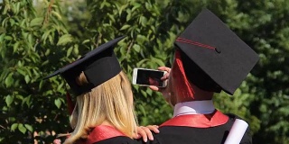 一对快乐的毕业生用智能手机拍摄毕业典礼视频