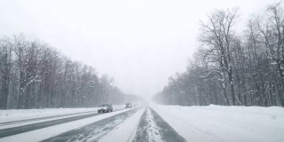 在下雪的乡村道路上驾驶POV。冬季雪山公路驾驶。森林。开车