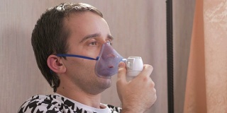 一个年轻人在家里拿着吸入器上的口罩。通过喷雾器治疗气道炎症。预防哮喘和咳嗽