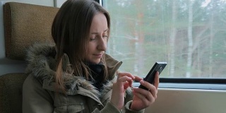 一个在火车上用智能手机的沉思女人