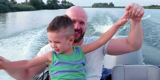 好爸爸在周末带着孩子，父亲和儿子花时间在一起，情绪反应在快速驾驶快艇