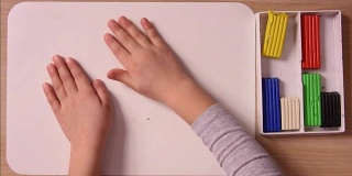 孩子的手在模型板上滚动一个橡皮泥球，特写，俯视图