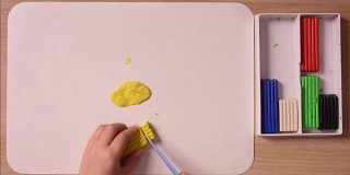 孩子剪下一堆黄色的橡皮泥做工艺品，特写，俯视图