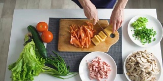 俯视图女人的手切蔬菜在一块木板上的披萨晚餐在厨房里