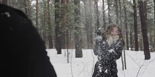 在一片冰雪覆盖的森林里，一对男女正在互相扔雪球
