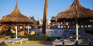 阳光度假酒店与蓝色的游泳池，棕榈树和日光浴床在埃及