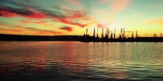 colorful sunset at sea harbor with cargo port cranes and epic vibrant sky