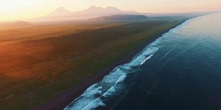 美丽的风景。日落时的大海和群山。乘着直升机沿着海浪飞行