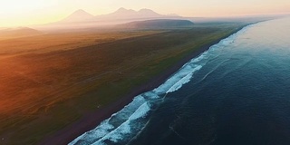 直升机在日落时分飞过海面飞向群山。在日出时飞过海洋。雾山