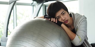 短发亚洲女孩在健身房练瑜伽。疲惫疲惫却依然微笑