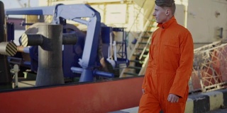 身穿橙色制服的港口工人正在货港工地上行走。Slowmotion