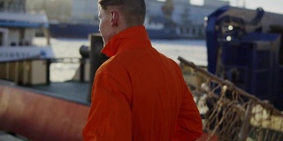 身穿橙色制服的港口工人正在货港工地上行走。Slowmotion