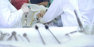 医院里的医生穿着防护服使用设备进行手术。