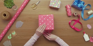 空中拍摄的女子用粉红色包装纸包装礼物的画面