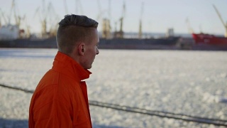 穿着橙色制服的港口工人正在海边散步。Slowmotion视频素材模板下载