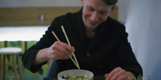 一个人试图用筷子吃面条的特写镜头。学习如何拿筷子。蔬菜面在日本餐厅用餐。