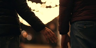 一对面目全非的情侣手牵着手走在夜晚的街道上