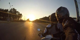 日落时分，两名男子骑着摩托车高速行驶在乡村公路上。朋友们骑着自行车向太阳高速前进，自拍。观点关闭
