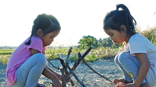 亚洲女孩玩干树枝与姐姐在日落