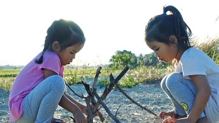 亚洲女孩玩干树枝与姐姐在日落视频素材模板下载