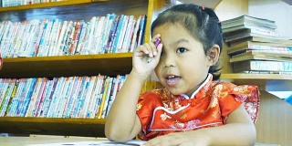 亚洲小女孩穿着中国衣服在图书馆画画