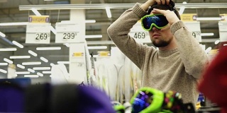 年轻人在超市试戴滑雪板眼镜