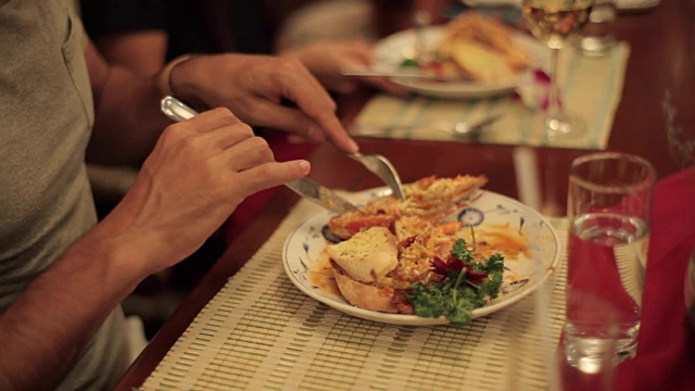 用刀叉在盘子里吃龙虾的人的手特写