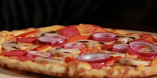 新鲜出炉的披萨配上意大利辣香肠、蘑菇、洋葱和胡椒。前视图