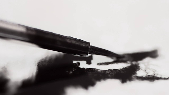 微距拍摄的画笔与黑色油漆在白纸上