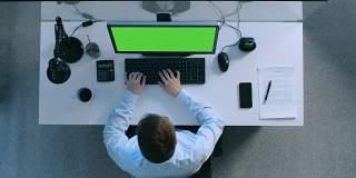 顶部视图勤奋的会计工作在他的办公桌上的一个绿色屏幕上的个人电脑。还在桌上签署了文件和手机。