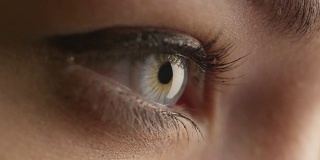 特写镜头的女人打开她的蓝色眼睛和聚焦她的视线。