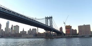低角度视角:在标志性的曼哈顿大桥下沿着东河巡航