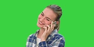 穿着休闲装的漂亮女人在打电话，在绿色屏幕上微笑，色度键