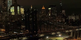 空中特写:夜晚，汽车穿过著名的曼哈顿大桥，灯光照亮了纽约