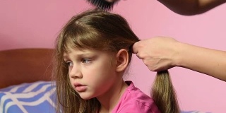 母亲为她的长发姑娘梳头，并把她们编成辫子