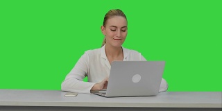快乐的女商人喜欢在笔记本电脑上工作，想象一下这个项目，然后在绿色屏幕上写下Chroma Key