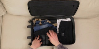 俯视图男性的手整理衣服和准备手提箱旅行