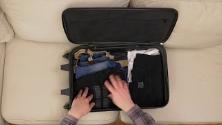 俯视图男性的手整理衣服和准备手提箱旅行视频素材模板下载